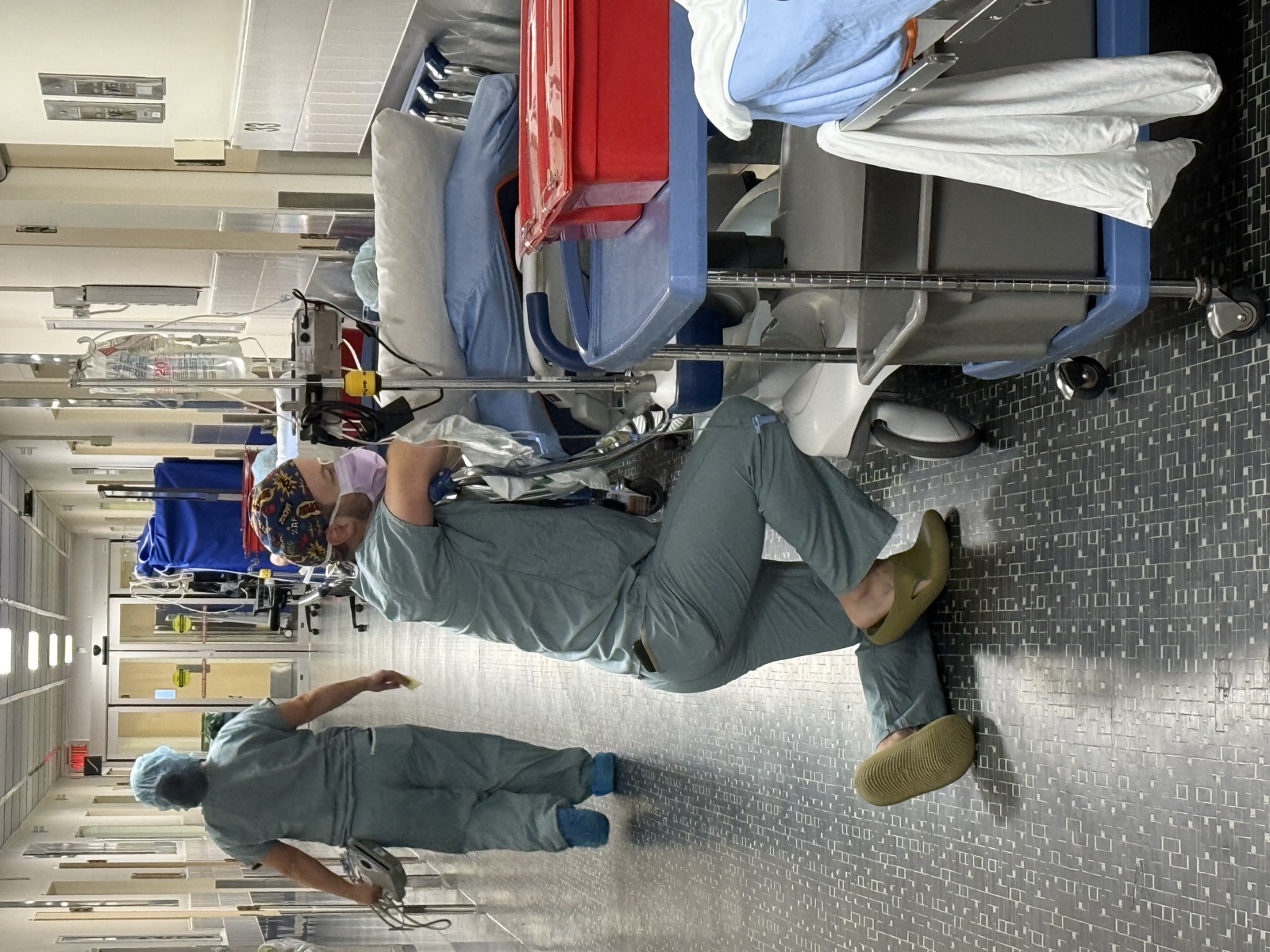 Lawrence kneeling beside a stretcher in an operating-room corridor